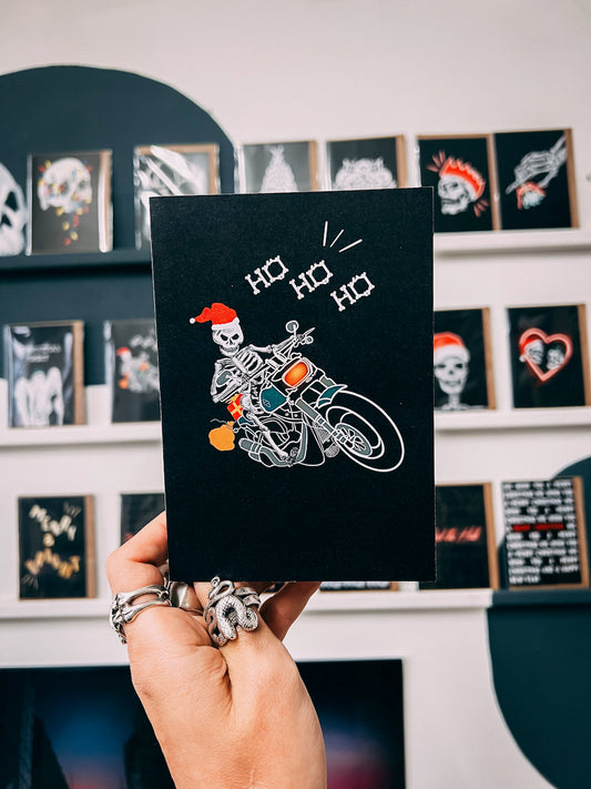 Wayward black greetings card with Biker Skeleton Santa Claus on a motorbike with bone lettering saying Ho Ho Ho