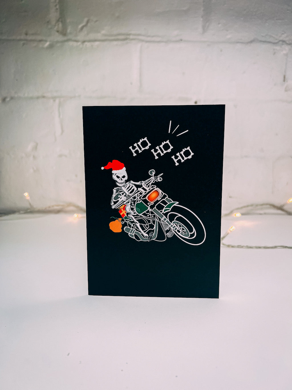 Wayward black greetings card with Biker Skeleton Santa Claus on a motorbike with bone lettering saying Ho Ho Ho