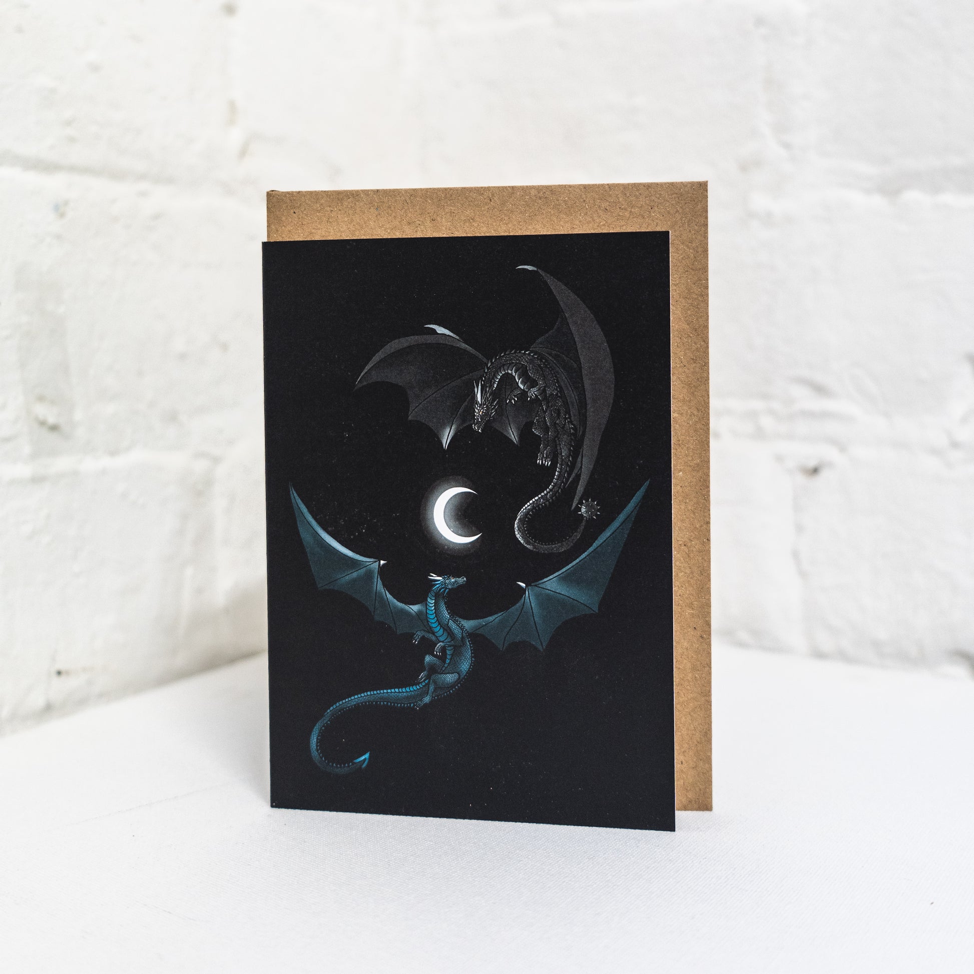 Two dragons flying round a crescent moon greetings card