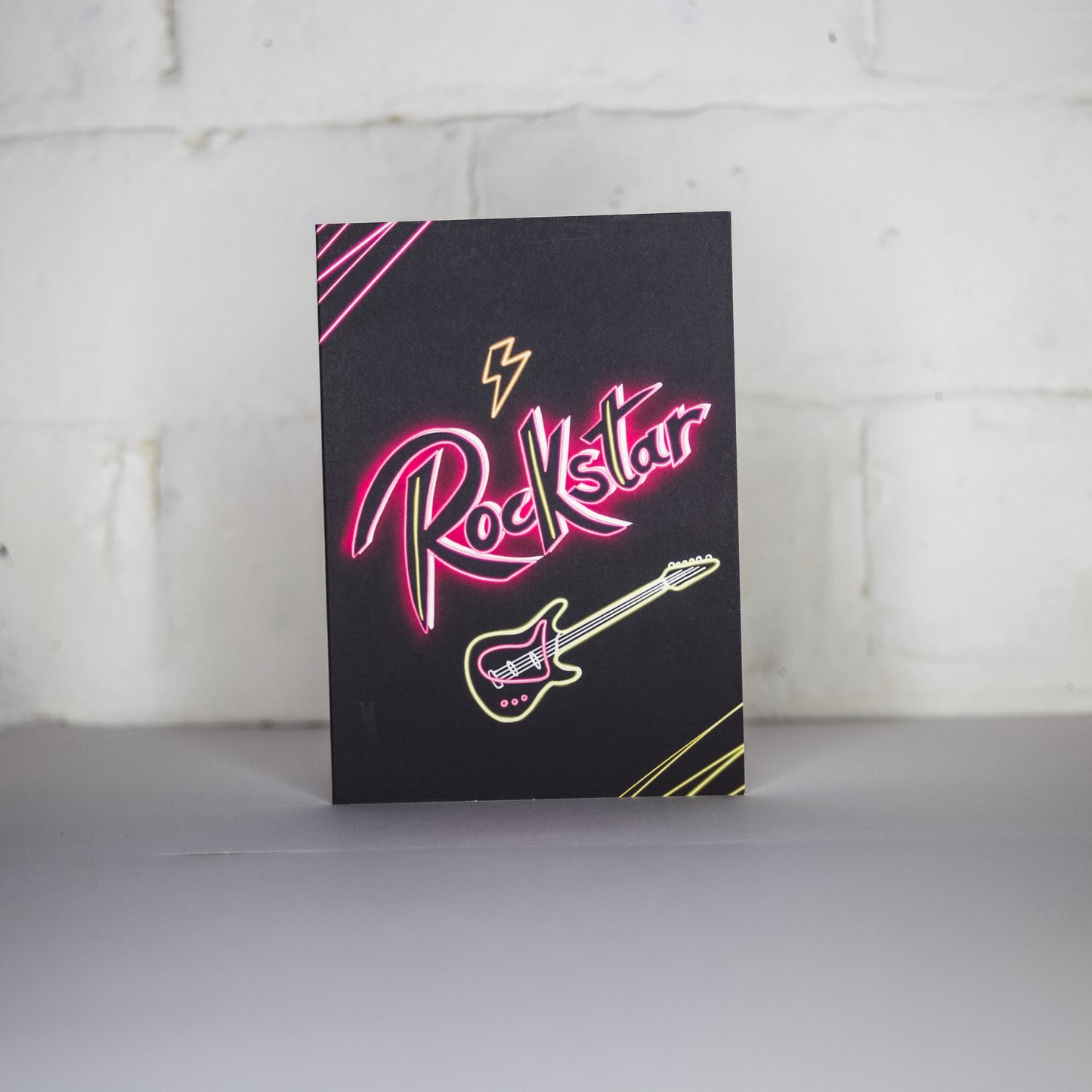 Black Greetings Card with Rockstar written in pink neon with a guitar