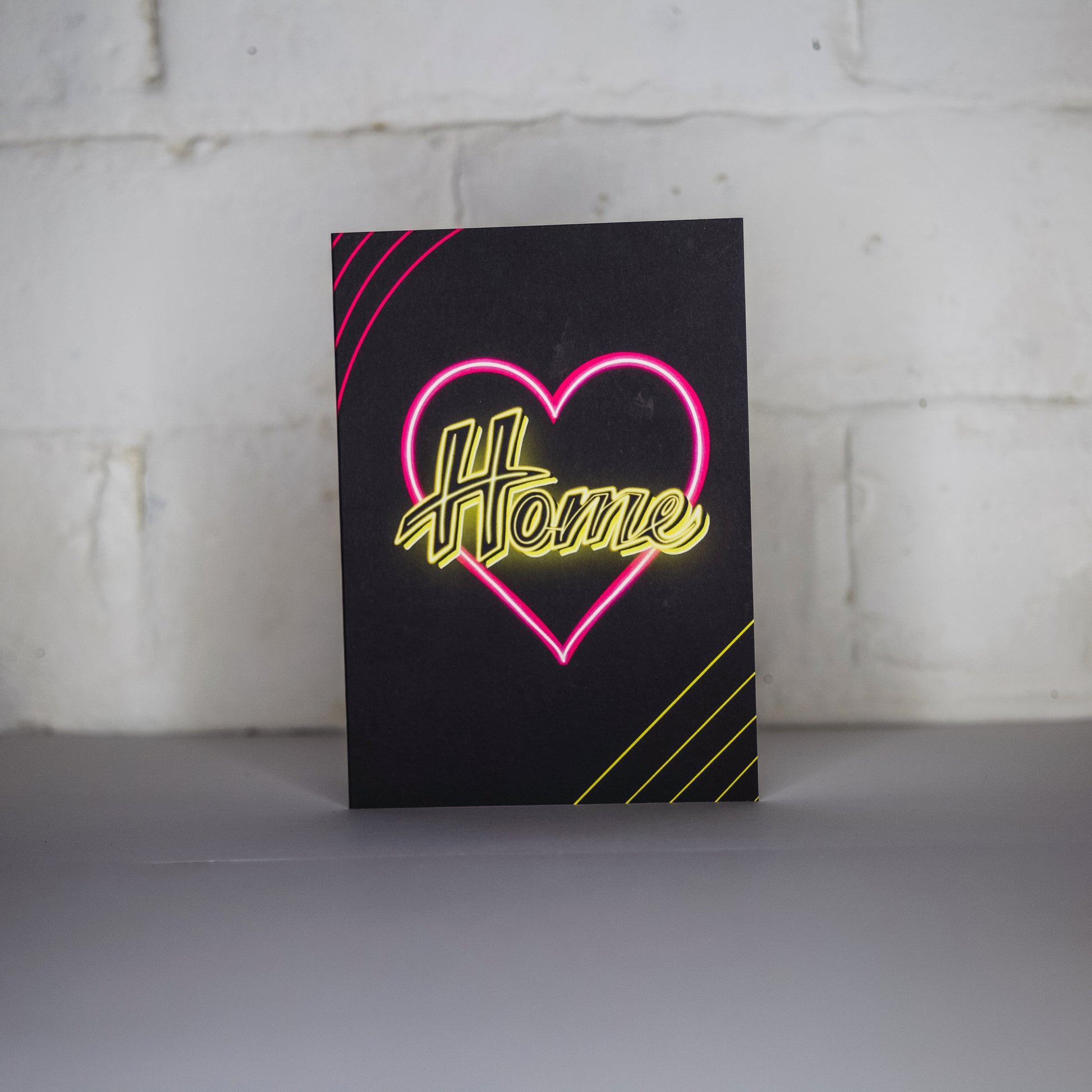 Black Greetings Card With Yellow Home Written in Pink Neon Heart by Wayward