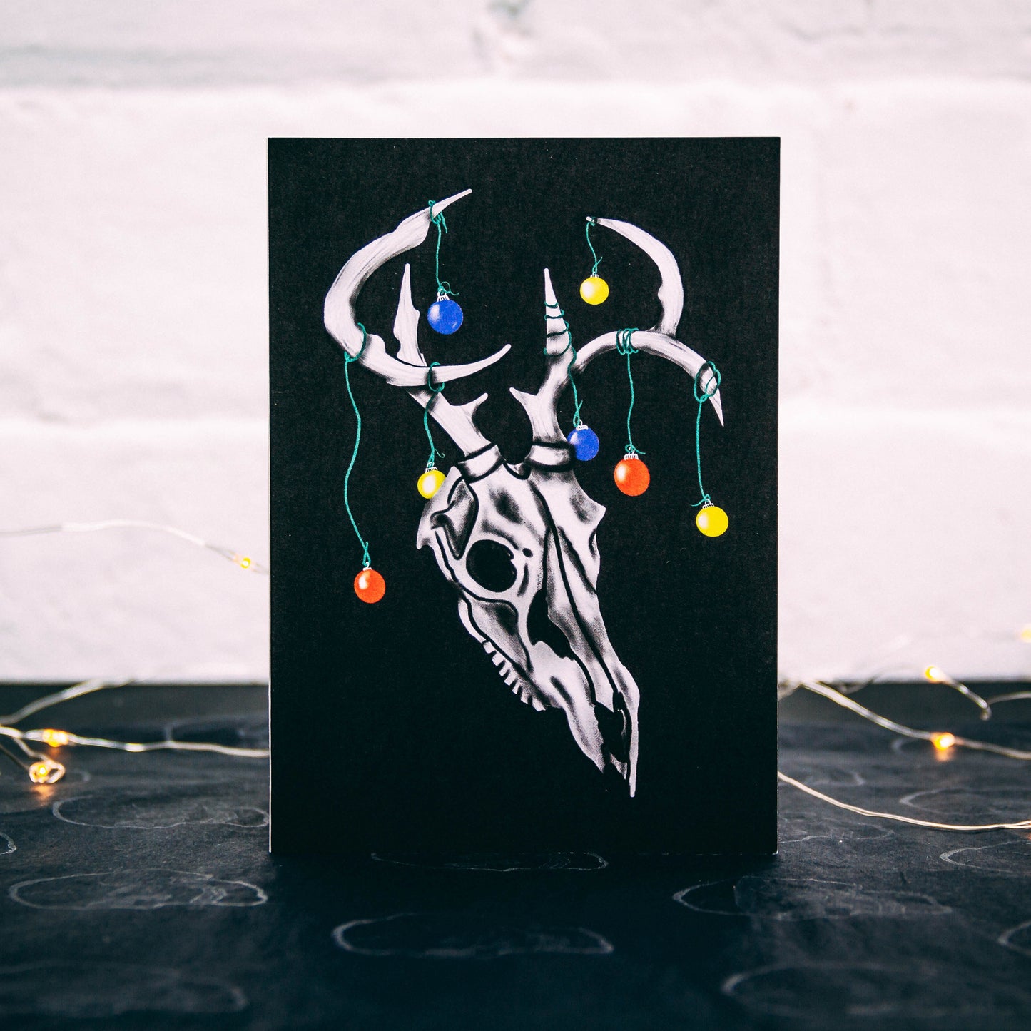 Black Christmas Card with Illustrated deer with Christmas baubles on its horns. Designed by Wayward