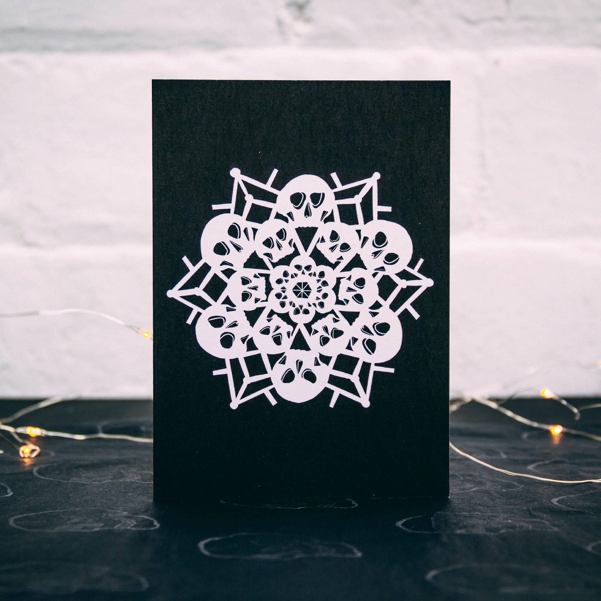White snowflake made of skulls on black background, christmas card by wayward