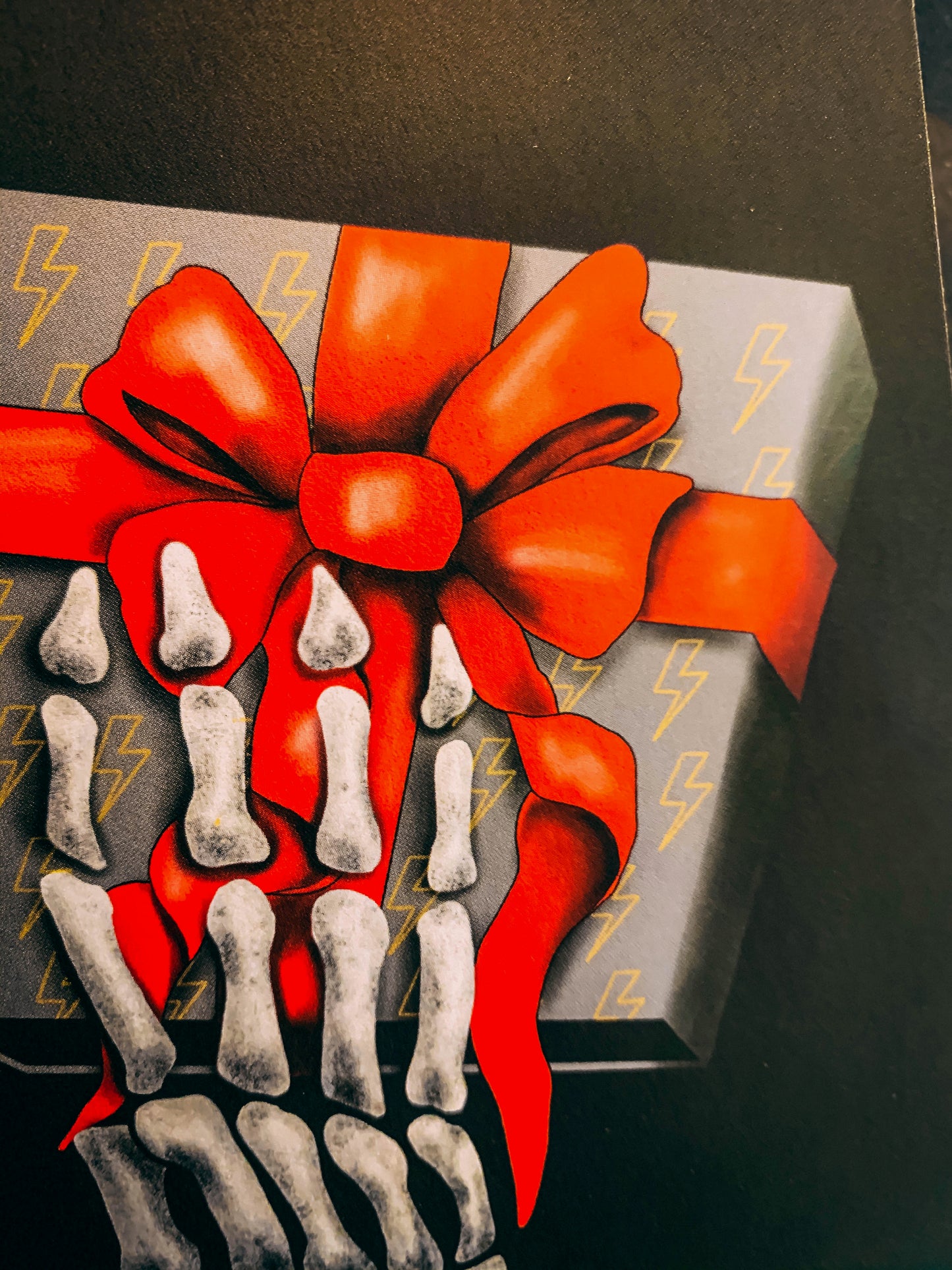 Black A6 greetings cards with skeleton hand holding a grey box with red ribbon close up by Wayward