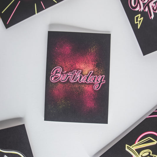Greetings card with pink neon birthday on pink and yellow paint splatter by wayward