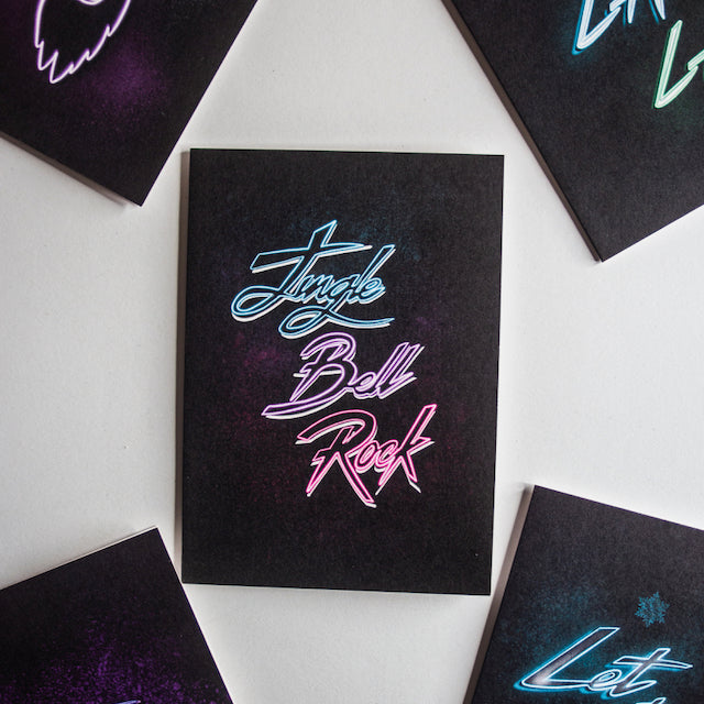 Jingle bell rock neon writing on black background christmas card by wayward