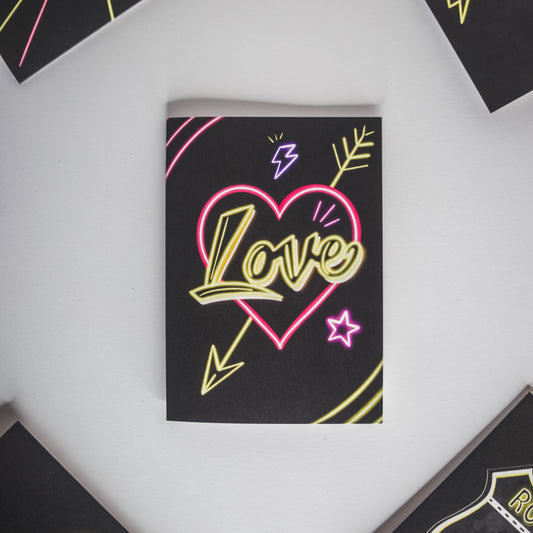 Black Greetings Card with Yellow Love Neon Writing in Pink Heart by Wayward
