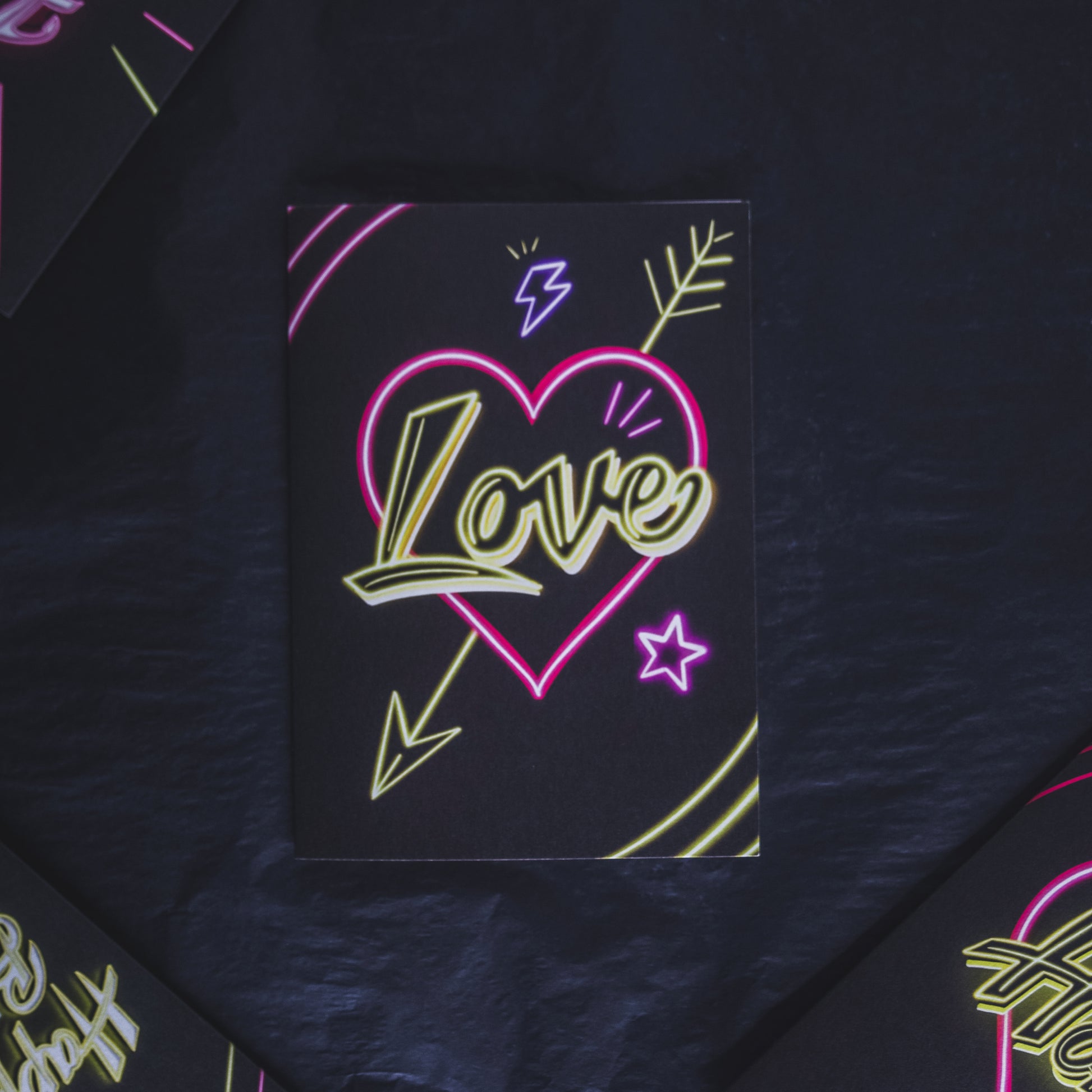 Black Greetings Card with Yellow Love Neon Writing in Pink Heart by Wayward