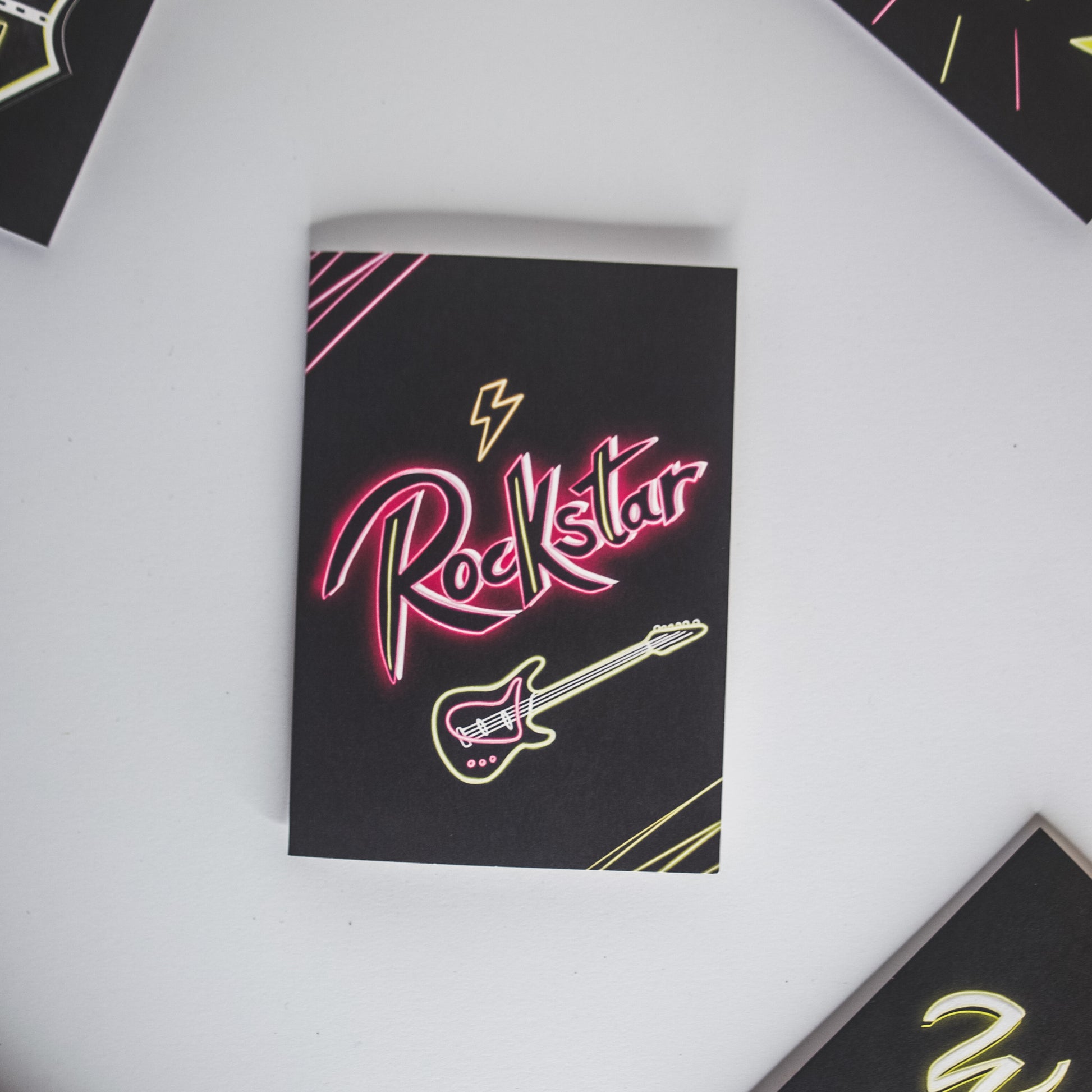 Black Greetings Card with Rockstar written in pink neon with a guitar