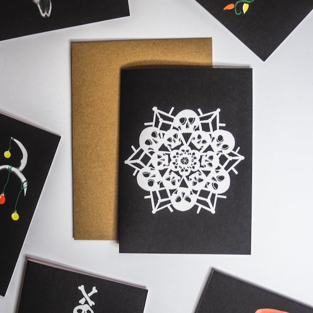 White snowflake made of skulls on black background, christmas card by wayward