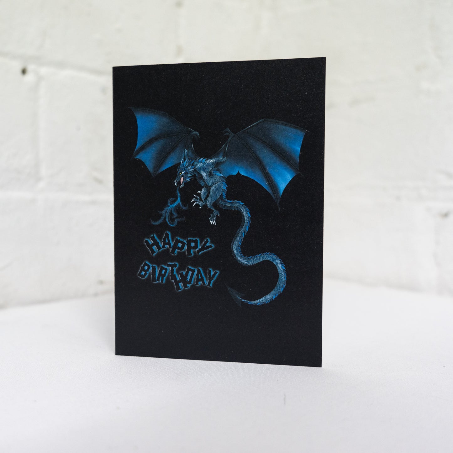 A Birthday Card Featuring A blue dragon on a black background by Wayward