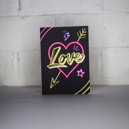 Black Greetings Card with Yellow Love Neon Writing in Pink Heart by Wayward
