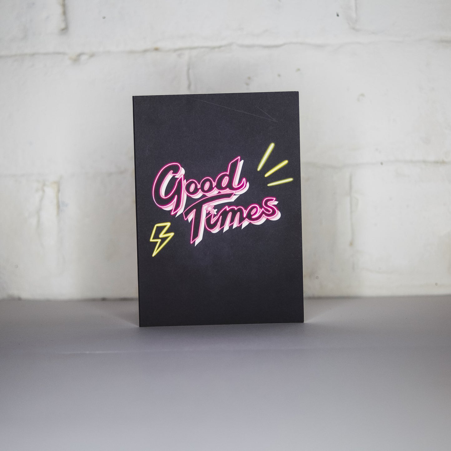Greetings card with black background and pink Good Times neon writing by Wayward