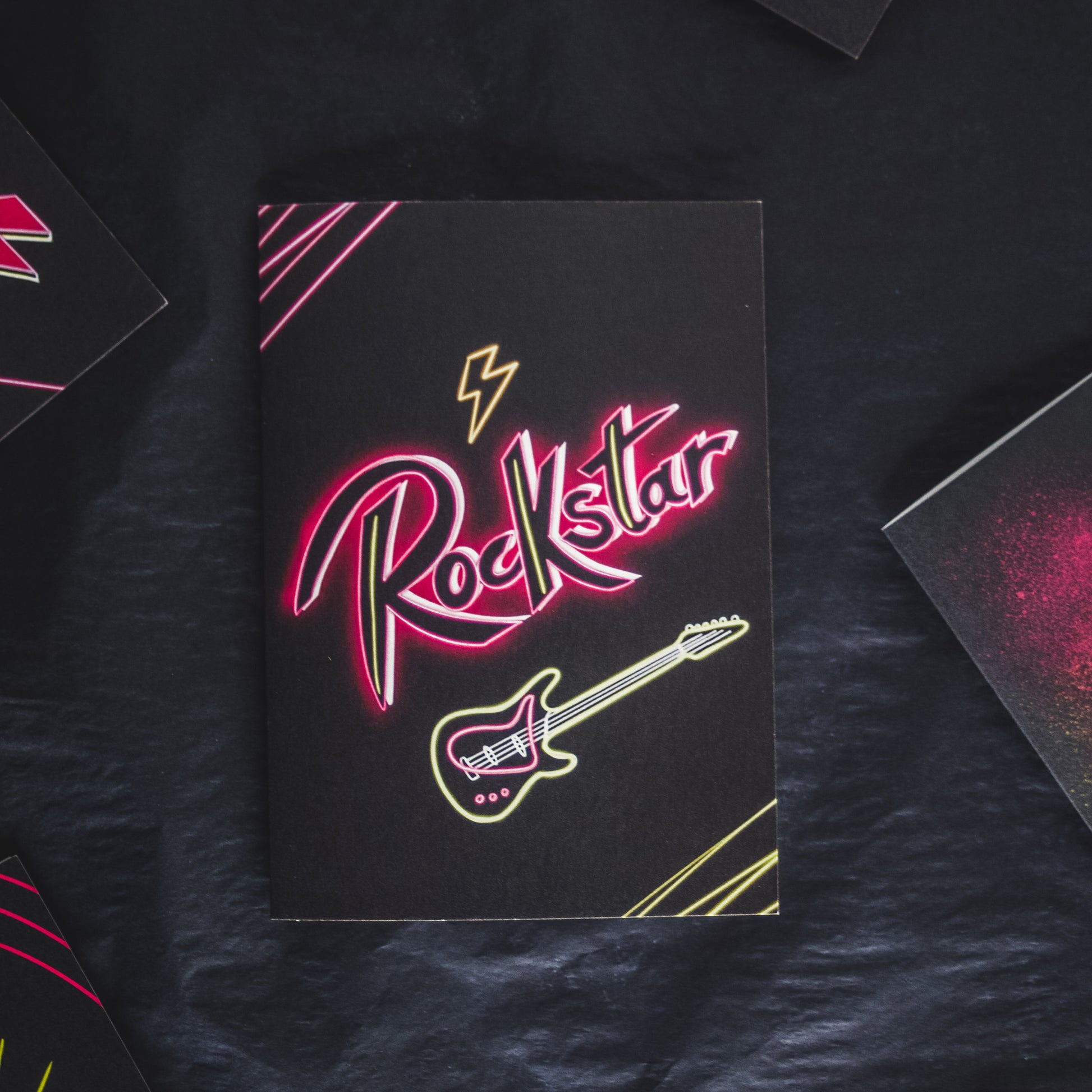 Black Greetings Card with Rockstar written in pink neon with a guitar 