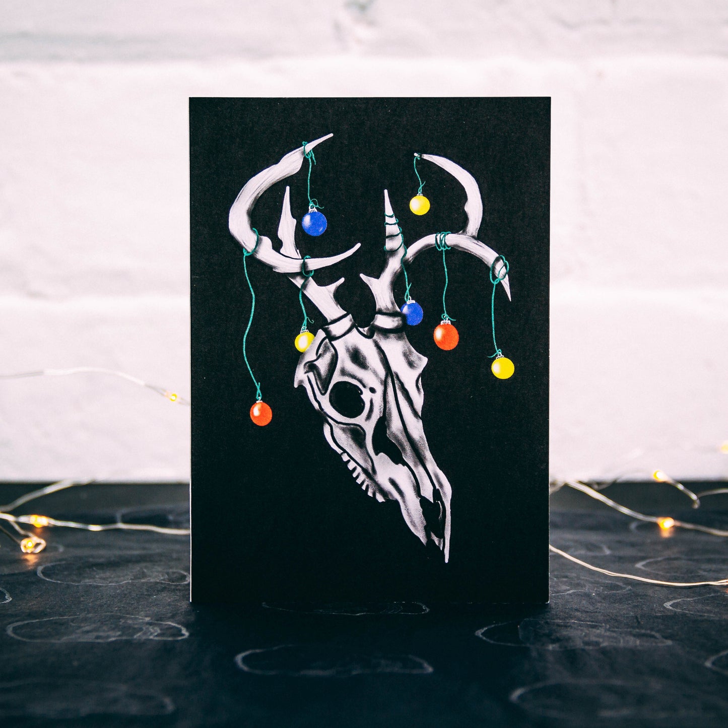 Black Christmas Card with Illustrated deer with Christmas baubles on its horns. Designed by Wayward 