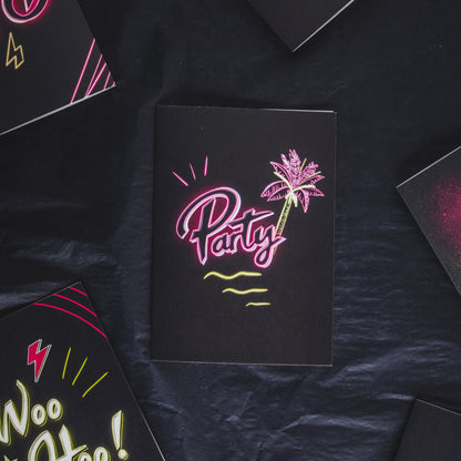 Black greetings card with party written in pink neon with a palm tree by wayward