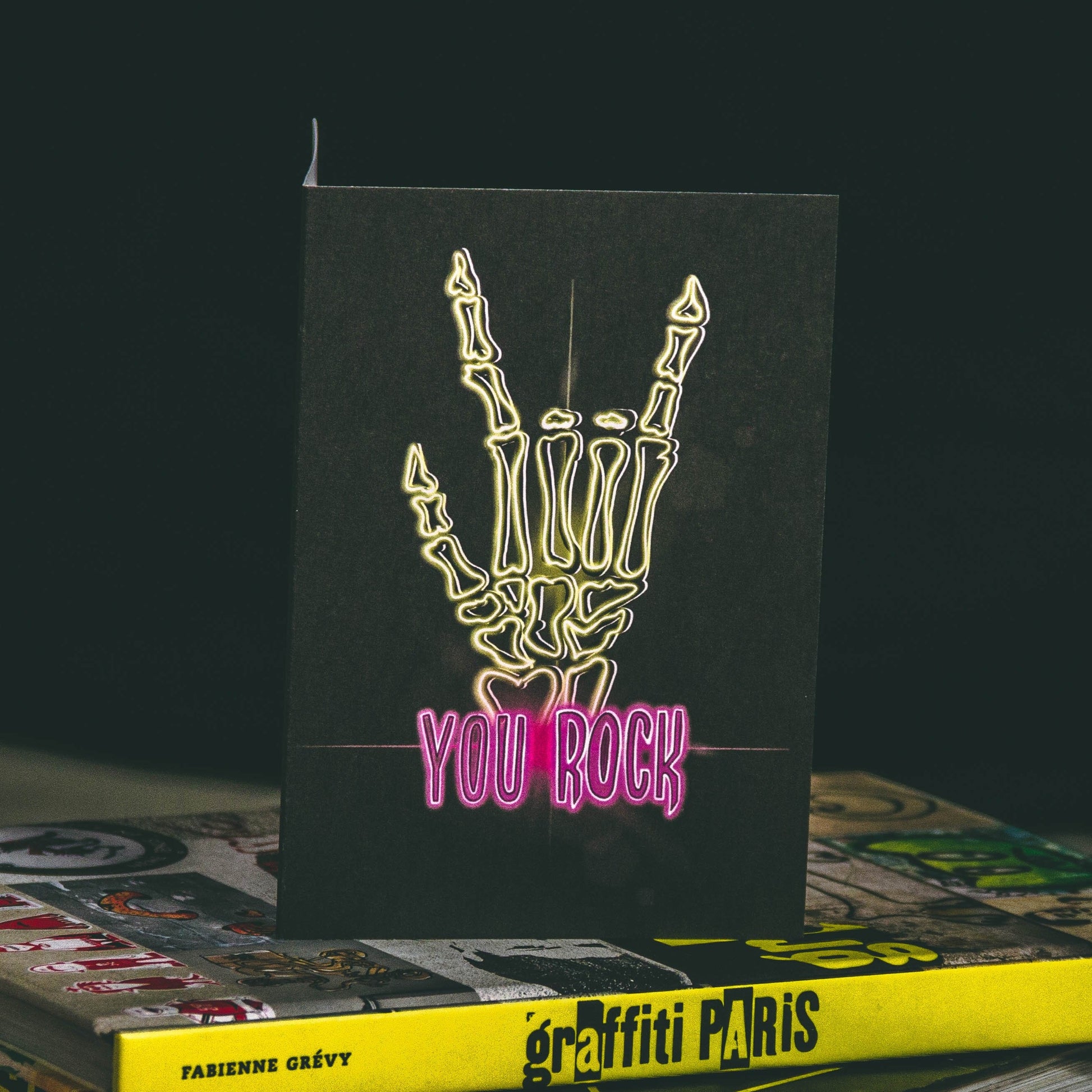 A6 Greeting Card with yellow neon skeleton rock hand and pink you rock writing by wayward