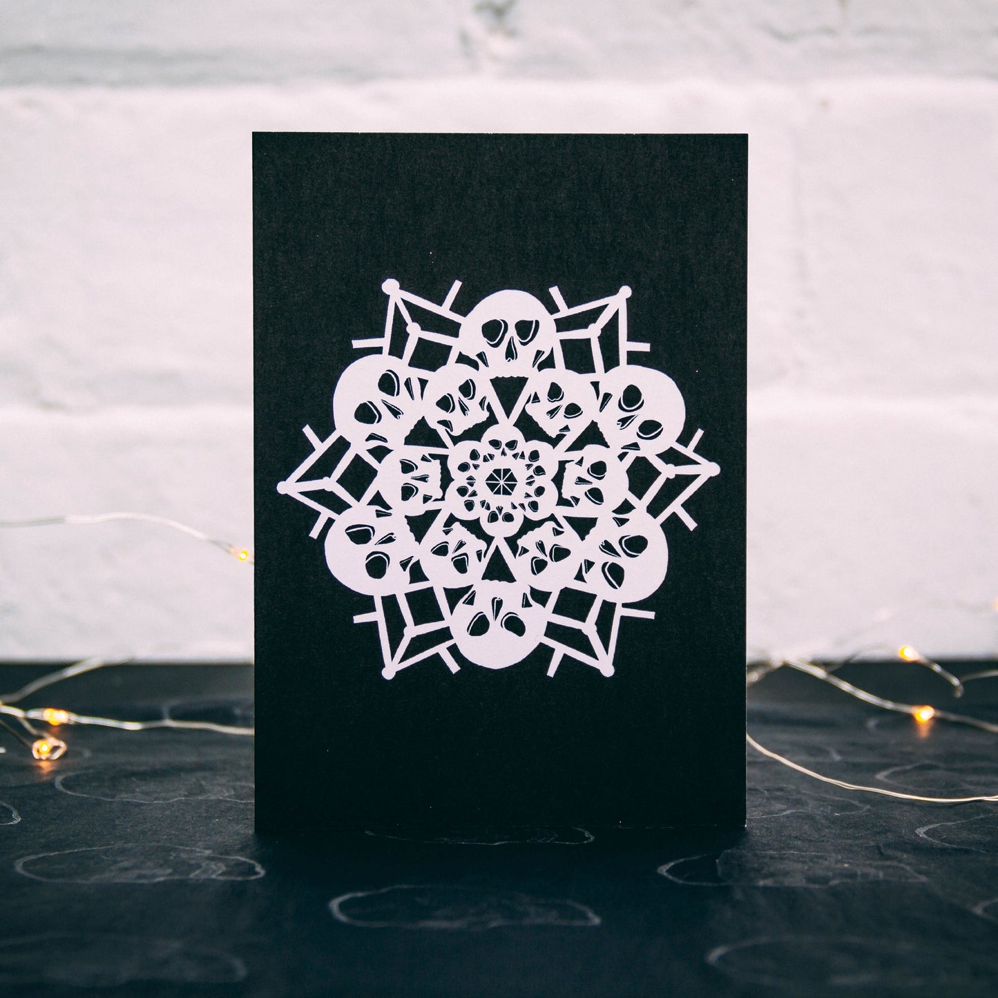 White snowflake made of skulls on black background, christmas card by wayward