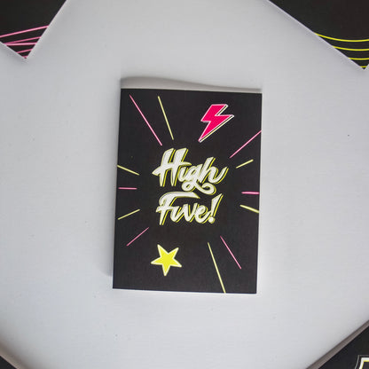 Black Greetings Card With White and Yellow Neon High Five Writing with Lightening Bolt and Star Design by Wayward