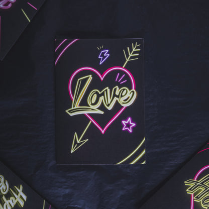 Black Greetings Card with Yellow Love Neon Writing in Pink Heart by Wayward