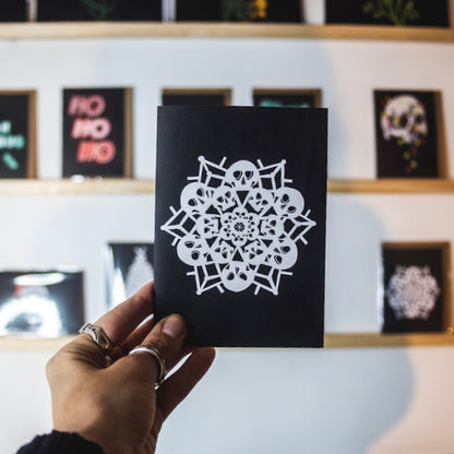 White snowflake made of skulls on black background, christmas card by wayward