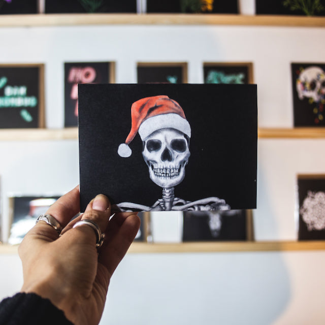 Skull with santa hat on black background christmas card by wayward
